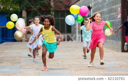 Kids with balloons running through streets Kids with balloons running through streets 82110781