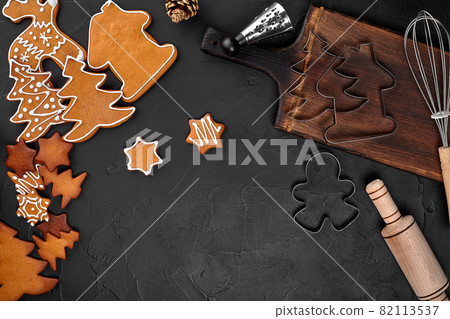 Christmas homemade gingerbread cookies, spices and cutting board on dark background with copy space for text top view. New year and christmas postcard 82113537
