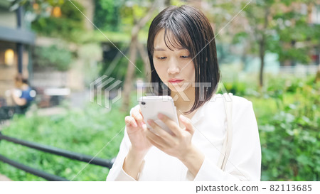A woman who uses a smartphone in the city 82113685