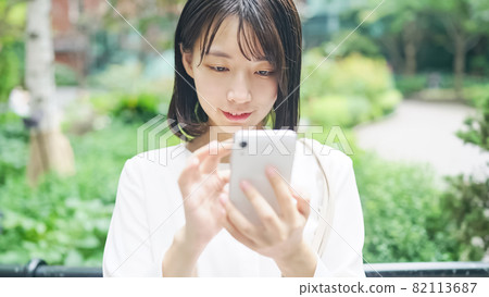 A woman who uses a smartphone in the city 82113687