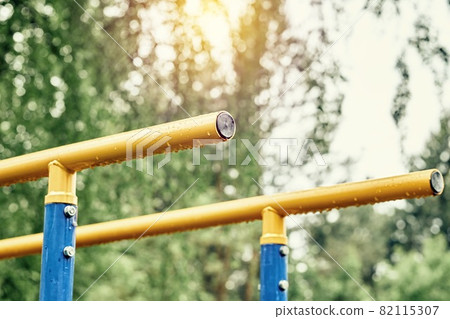Yellow bars with hanging rain drops at sports ground in park Yellow bars with hanging rain drops at sports ground in park 82115307