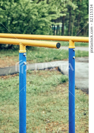 Yellow bars with hanging rain drops at sports ground in park Yellow bars with hanging rain drops at sports ground in park 82115334