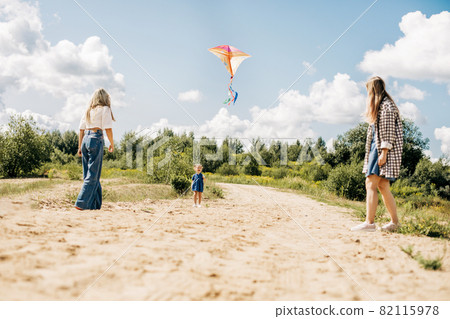 A mother flies a kite with her daughters during a family vacation in the country A mother flies a kite with her daughters during a family vacation in the country 82115978
