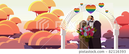 newlywed gay couple with flowers kissing near wedding arch transgender love LGBT community wedding newlywed gay couple with flowers kissing near wedding arch transgender love LGBT community wedding 82116393