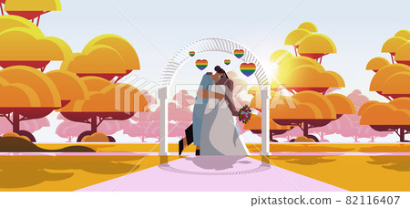 newlywed lesbian couple with flowers kissing near wedding arch transgender love LGBT community wedding celebration newlywed lesbian couple with flowers kissing near wedding arch transgender love LGBT community wedding celebration 82116407