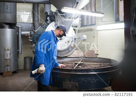 Workman checking quality of roasted coffee 82117191