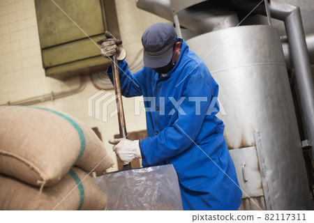 Man in uniform getting coffee ready for roasting Man in uniform getting coffee ready for roasting 82117311