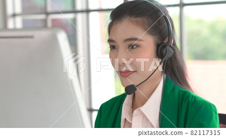 Businesswoman wearing headset working actively in office 82117315