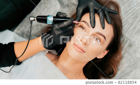 Make-up master performs the procedure of permanent eyebrow makeup 82118854