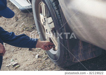 Mechanic man hands checking car tires outdoor on site service auto garage for automotive mobile center services. Technician workshop repair checking tyres car motor vehicles service mechanical hands 82119022