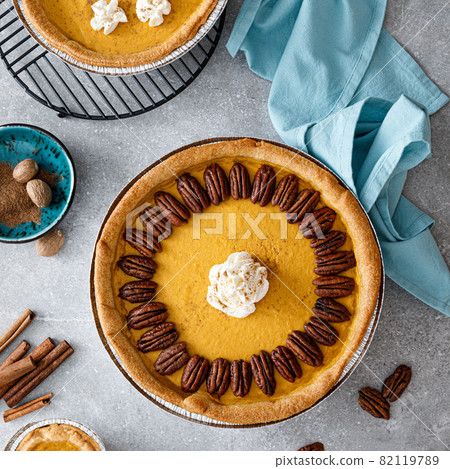 Pumpkin pie with cinnamon, pecan nuts and whipped cream for Thanksgiving, top view. Pumpkin pie with cinnamon, pecan nuts and whipped cream for Thanksgiving, top view. 82119789