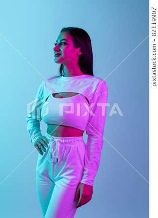 Studio portrait of young beautiful girl isolated over blue background in neon light 82119907