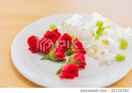Red and white edible flowers served on a plate Red and white edible flowers served on a plate 82120762
