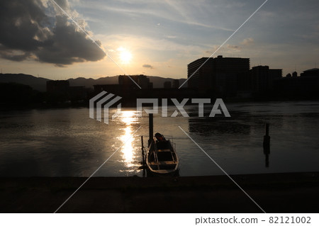 The evening sun, gray clouds, thin clouds, the surface of the sun road, and the river with fishing boats are in focus. Buildings and mountains are dark. The evening sun, gray clouds, thin clouds, the surface of the sun road, and the river with fishing boats are in focus. Buildings and mountains are dark. 82121002