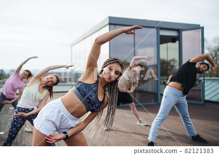 Group of young people doing exercise outdoors on terrace, sport and healthy lifestyle concept. 82121383