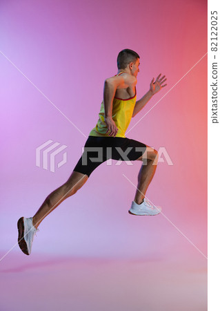 Back side view portrait of young male athlete running isolated over gradient studio background. In motion Back side view portrait of young male athlete running isolated over gradient studio background. In motion 82122025