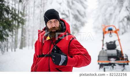 Paramedic man from mountain rescue service with walkie talkie outdoors in winter in forest. 82122256
