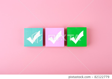 Three checkmarks on colorful blocks against pastel pink background  82122779