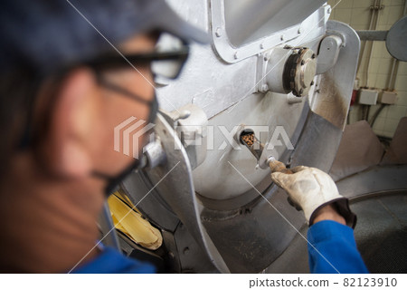 Man checking quality of roasted coffee Man checking quality of roasted coffee 82123910