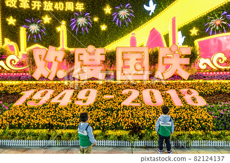 Twin boys looking at decorative stand set up to celebrate the National Day of China Twin boys looking at decorative stand set up to celebrate the National Day of China 82124137