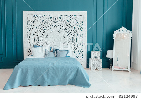 Beautiful luxury classic clean interior bedroom in white and deep blue color with king-size bed and chic carved furniture. Bright modern stylish interior bedroom and living room in minimalist style. 82124988