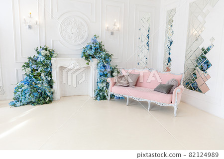 Beautiful luxury classic clean interior living room in white color with pink sofa firepalce flower composition. Bright modern stylish interior living room with furniture in classic minimalist style. Beautiful luxury classic clean interior living room in white color with pink sofa firepalce flower composition. Bright modern stylish interior living room with furniture in classic minimalist style. 82124989