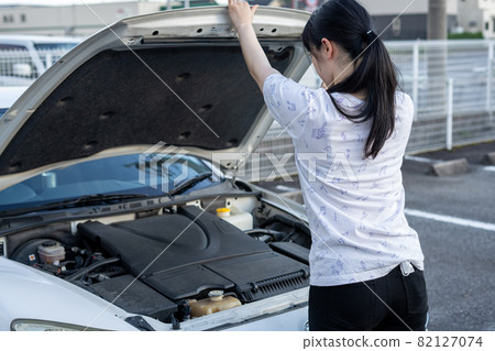 Woman opening the hood of a car Woman opening the hood of a car 82127074