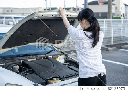 Woman opening the hood of a car 82127075