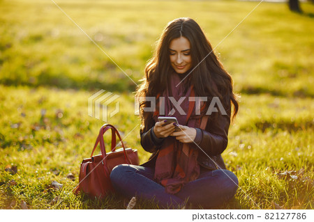 brunette girl using phone while at the park 82127786