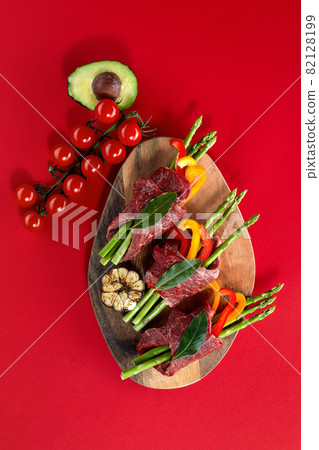 Baking pan with uncooked beef roulades and fresh vegetable trimmings ready for cooking on a white background Baking pan with uncooked beef roulades and fresh vegetable trimmings ready for cooking on a white background 82128199