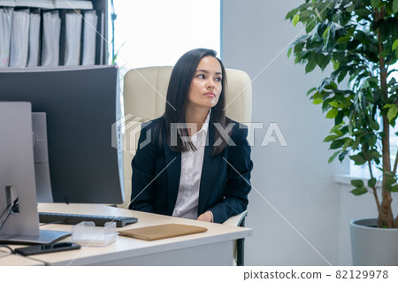 Young contemporary businesswoman sitting by workplace 82129978
