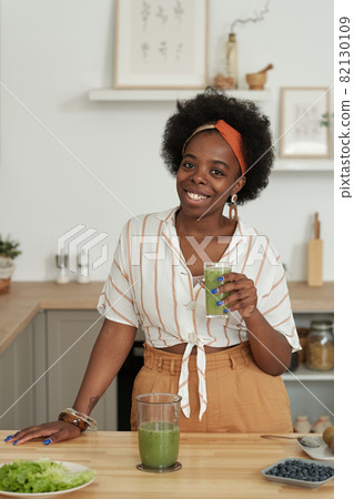 Young cheerful African woman with glass of smoothie 82130109
