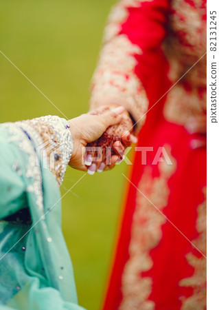 hindu bride walks behind husband holding garb 82131245