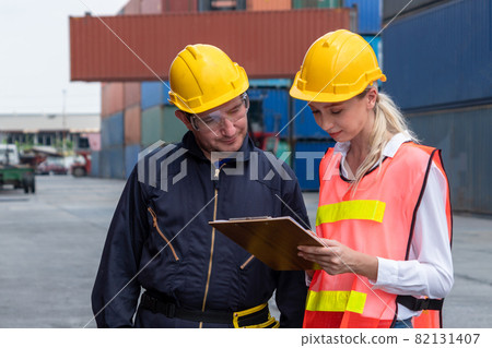 Industrial worker works with co-worker at overseas shipping container yard 82131407