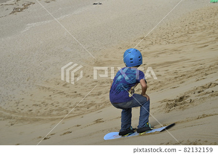 A boy sliding on a sandboard in the Tottori sand dunes 82132159