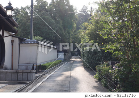 A landscape with Kyoto-like roads, utility poles, lamps, and electric wires surrounded by green trees, hedges, buildings, and earthen walls that are totally hazy due to strong sunlight. A landscape with Kyoto-like roads, utility poles, lamps, and electric wires surrounded by green trees, hedges, buildings, and earthen walls that are totally hazy due to strong sunlight. 82132710