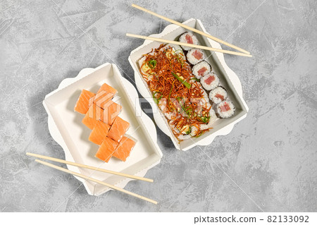 Tasty sushi rolls in disposable kraft paper boxes. Concept delivery service Japan food in eco container, flat lay Tasty sushi rolls in disposable kraft paper boxes. Concept delivery service Japan food in eco container, flat lay 82133092