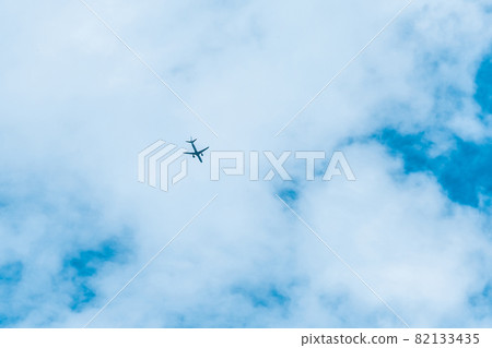 The plane flies in a big blue sky with white clouds background The plane flies in a big blue sky with white clouds background 82133435