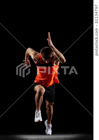 Full-length front view portrait of young male professional athlete running, training isolated over black studio background Full-length front view portrait of young male professional athlete running, training isolated over black studio background 82134797