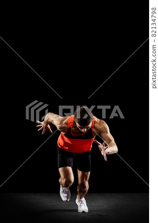 Full-length front view portrait of young male professional athlete running, training isolated over black studio background Full-length front view portrait of young male professional athlete running, training isolated over black studio background 82134798