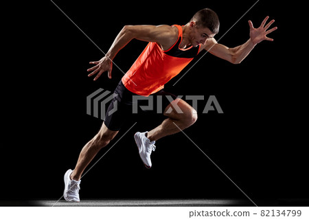 Full-length back view portrait of young male professional athlete running, training isolated over black studio background Full-length back view portrait of young male professional athlete running, training isolated over black studio background 82134799