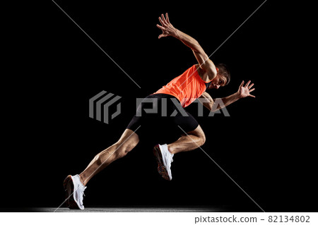 Full-length back view portrait of young male professional athlete running, training isolated over black studio background 82134802