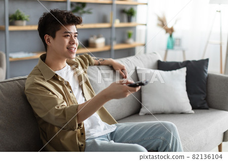 Happy asian guy spending weekend watching tv 82136104