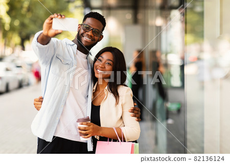 Happy black couple taking selfie after shopping at mall Happy black couple taking selfie after shopping at mall 82136124