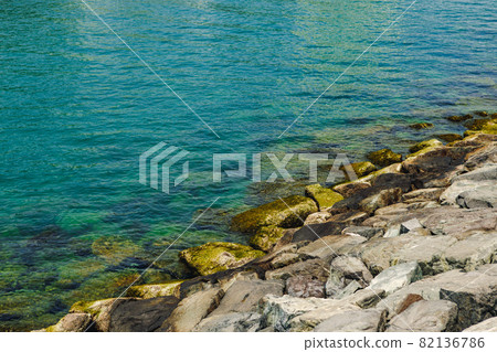 Close up of stones and clear water on the shore of a beach 82136786
