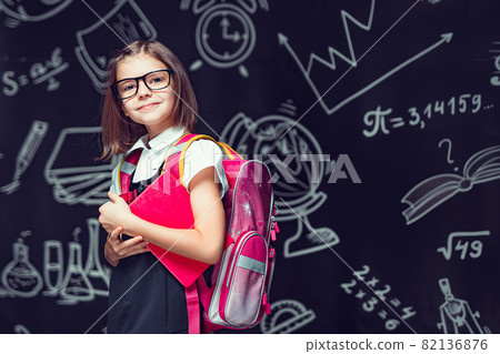 Cute pupil in glasses preparing to go to school with backpack and book in hands. Back to school Cute pupil in glasses preparing to go to school with backpack and book in hands. Back to school 82136876