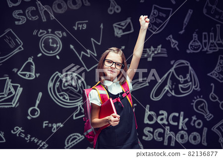 Happy pupil in glasses preparing to go to school holding book raising hand up. Back to school Happy pupil in glasses preparing to go to school holding book raising hand up. Back to school 82136877
