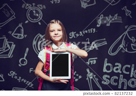 Little pupil preparing to go to school with backpack showing the tablet. Back to school concept  82137232