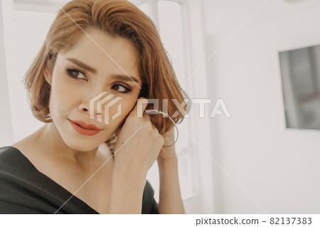Beautiful woman and her earrings in her apartment room. Beautiful woman and her earrings in her apartment room. 82137383