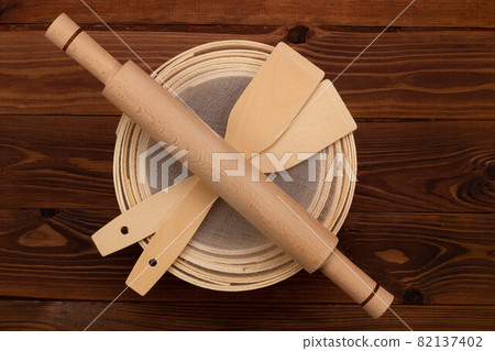 Antique traditional flour sieve, made from beech wood and fine wire mesh, dough rolling pin and culinary spatulas on a brown background. Set for sifting flour before cooking and baking. Top view 82137402